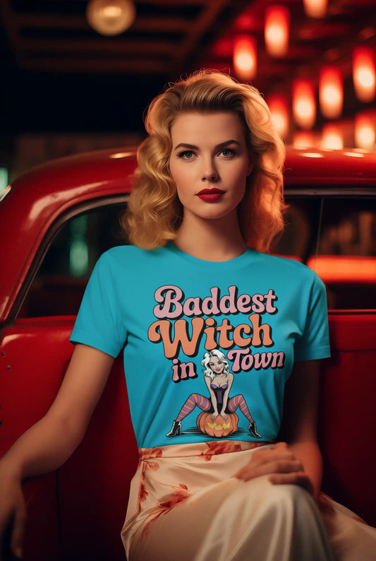 A woman in a blue "Baddest Witch in Town" t-shirt sits in a red car.