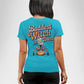 A woman from behind wears a blue t-shirt with "Baddest Witch in Town" and a witch graphic.