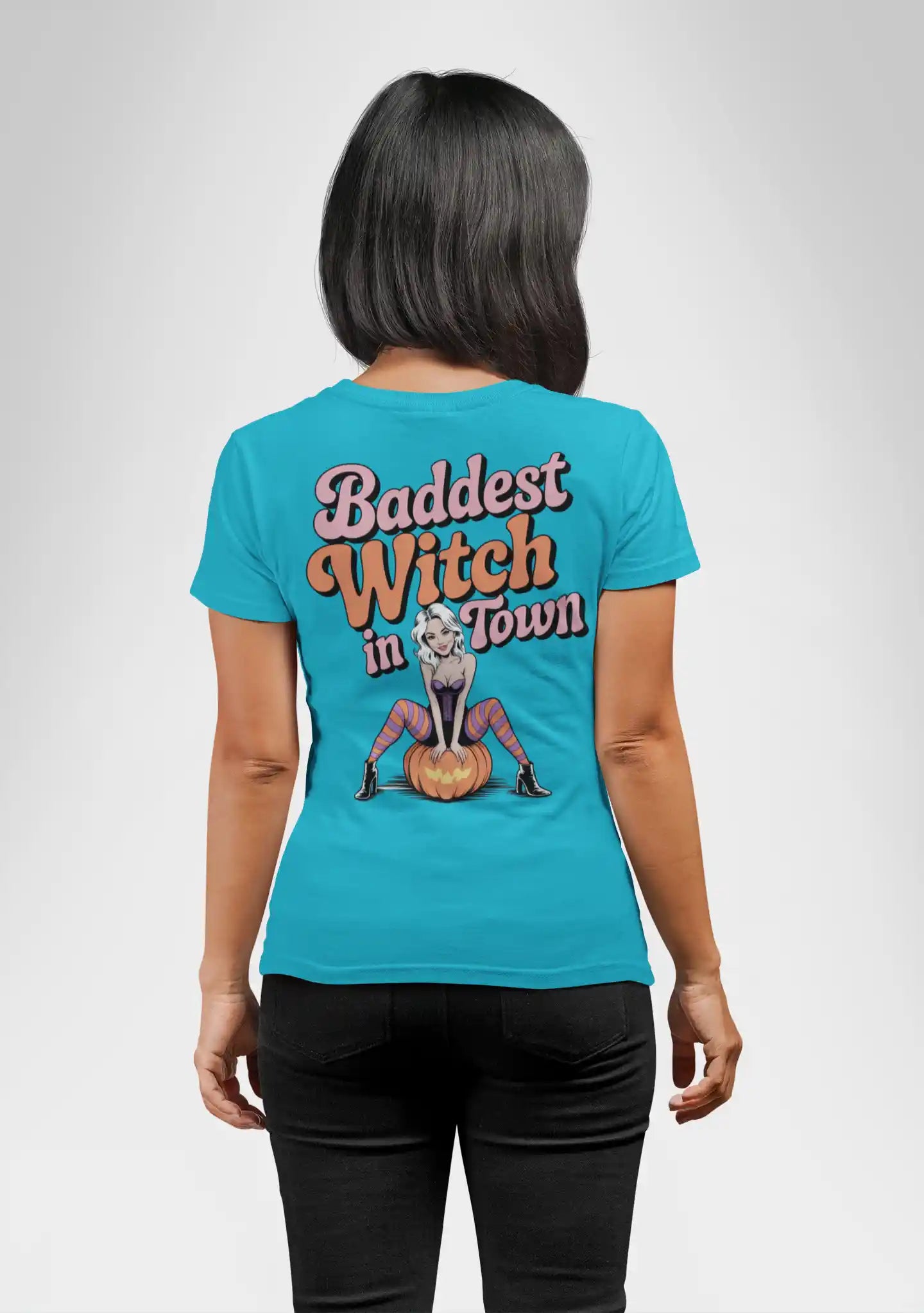 A woman from behind wears a blue t-shirt with "Baddest Witch in Town" and a witch graphic.