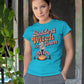 A woman wears a blue t-shirt with "Baddest Witch in Town" and a witch on a pumpkin.