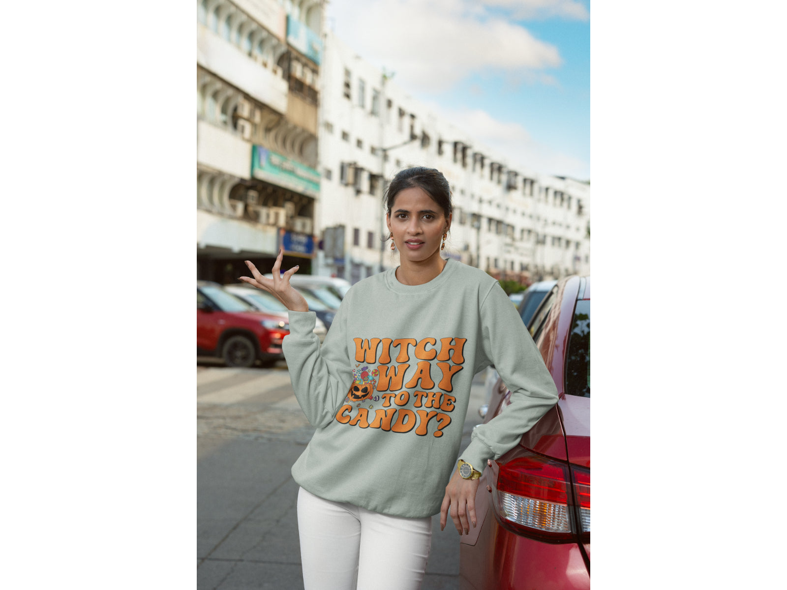A woman wears a light gray "Witch Way to the Candy" Halloween sweatshirt.