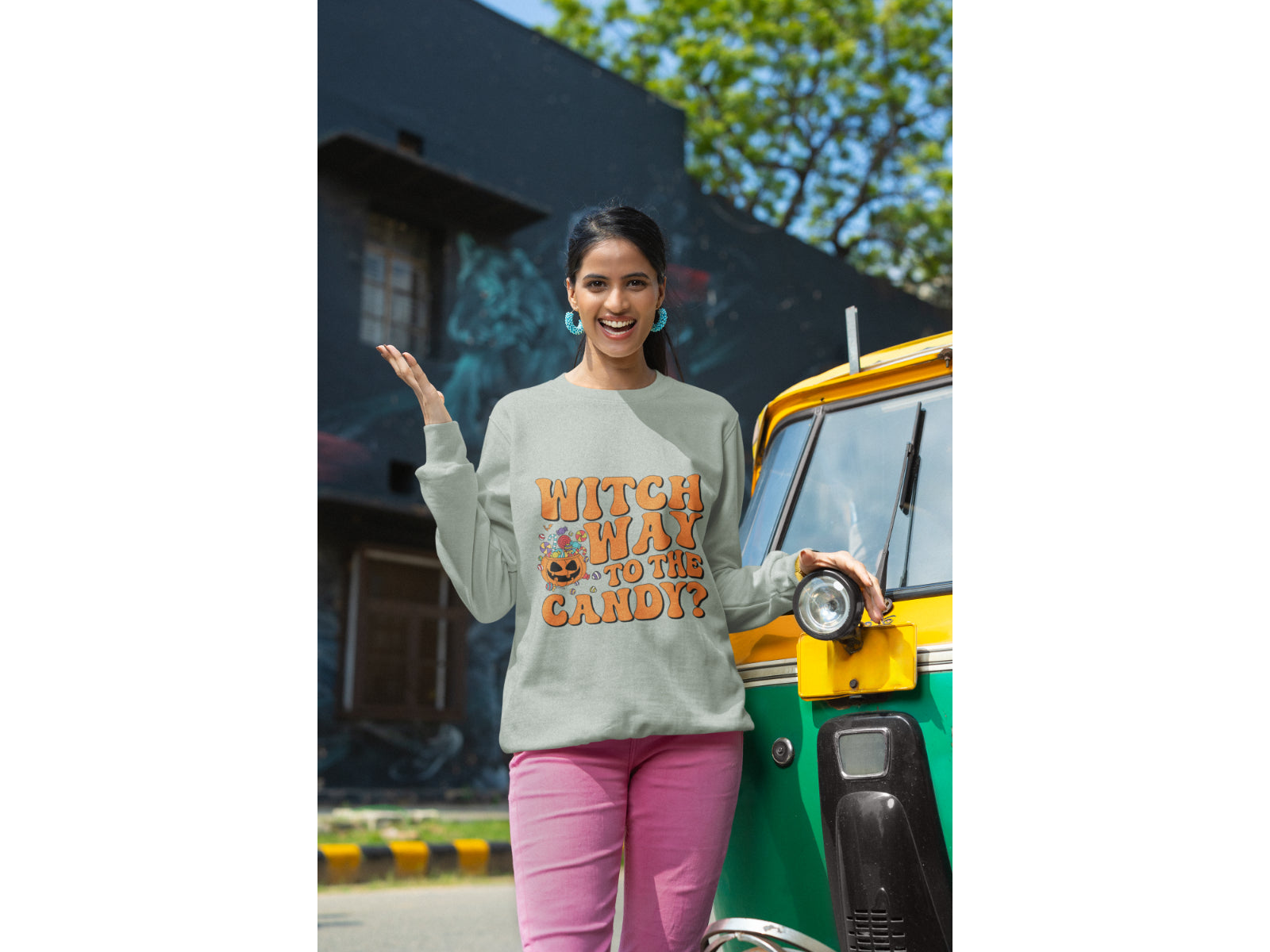 A woman wears a grey "Witch Way to the Candy" Halloween sweatshirt.