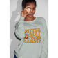 A woman wears a light gray sweatshirt with "Witch Way to the Candy?" in orange text.