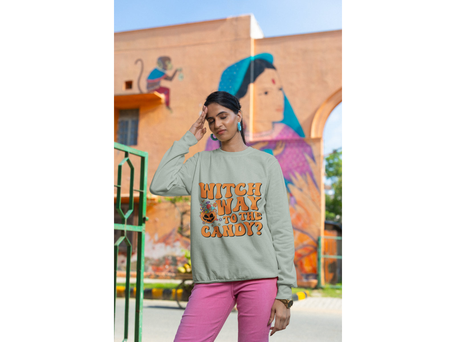 A woman wears a light gray "Witch Way to the Candy?" Halloween sweatshirt.