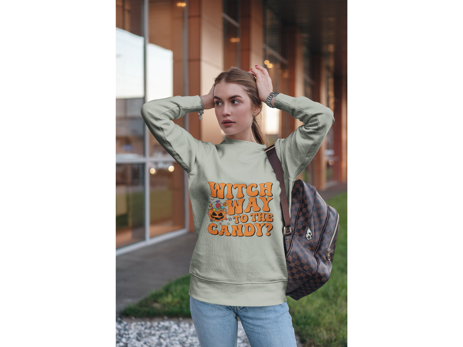 A woman wears a light green "Witch Way to the Candy?" Halloween sweatshirt.