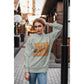 A woman wears a grey "Witch Way to the Candy" Halloween sweatshirt.