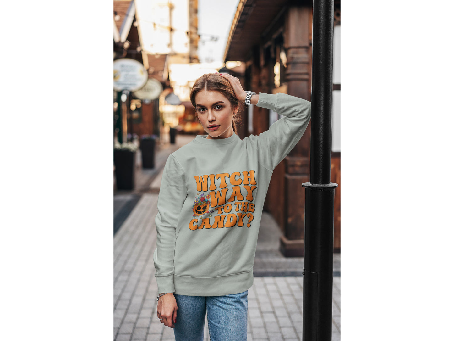A woman wears a grey "Witch Way to the Candy" Halloween sweatshirt.