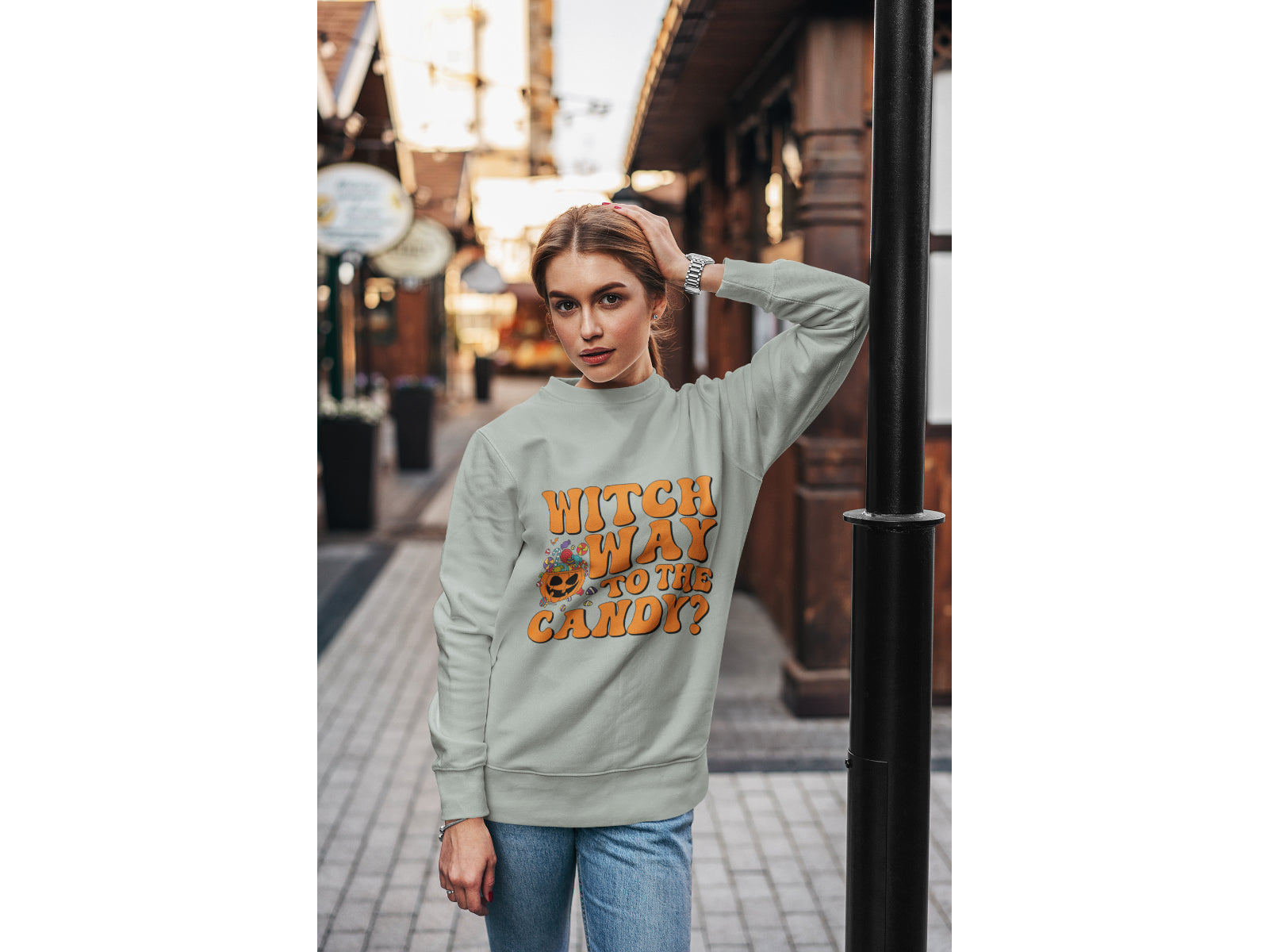 A woman wears a grey "Witch Way to the Candy" Halloween sweatshirt.
