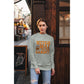 A woman wears a light grey "Witch Way to the Candy" Halloween sweatshirt.