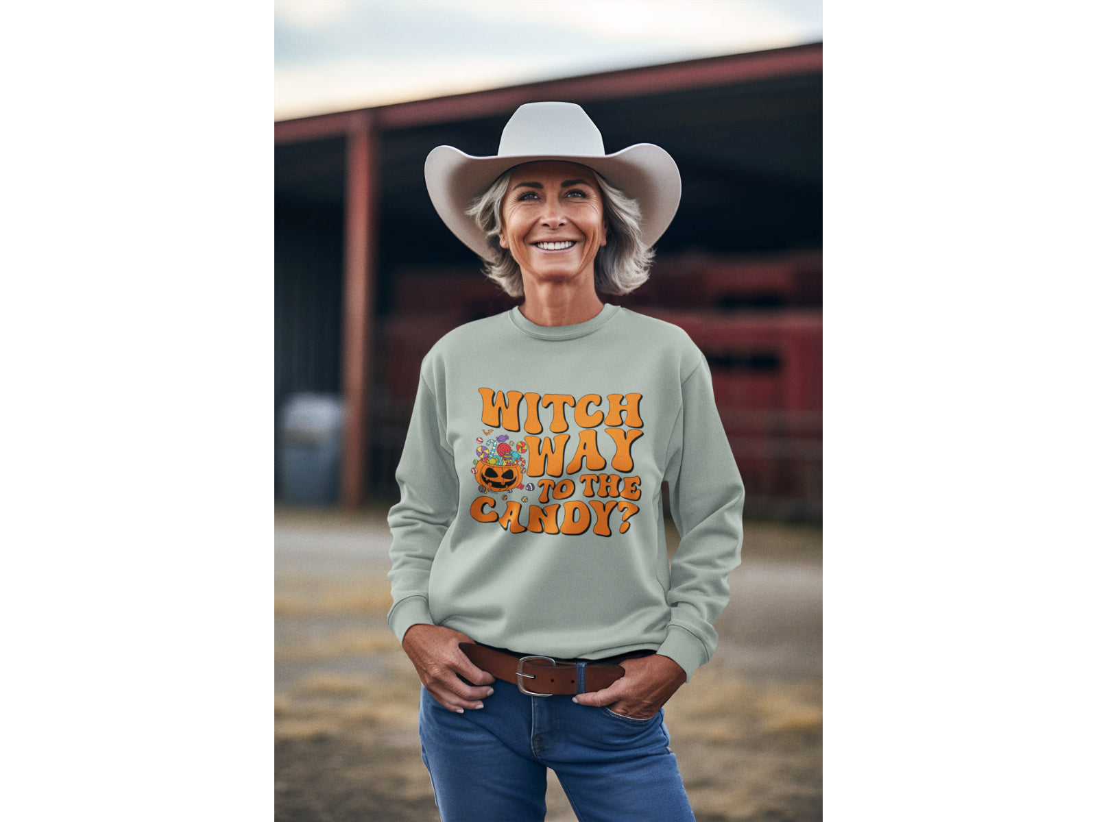 A woman in a cowboy hat wears a light green "Witch Way to the Candy" Halloween sweatshirt.