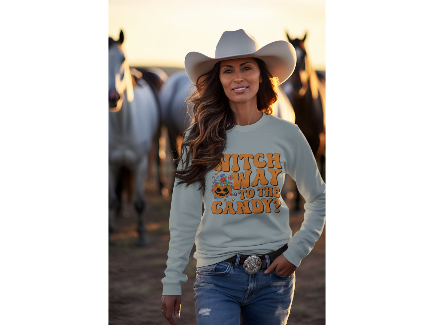 A woman in a cowboy hat and jeans wears a light blue "Witch Way to the Candy" sweatshirt.