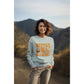 A woman smiles wearing a light blue "Witch Way to the Candy?" Halloween sweatshirt.