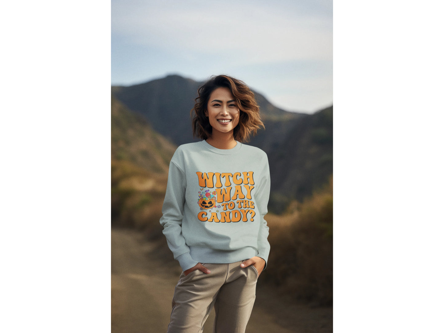 A woman smiles wearing a light blue "Witch Way to the Candy?" Halloween sweatshirt.