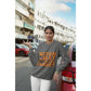 A woman wears a dark gray sweatshirt with "Witch Way to the Candy?" in orange text.