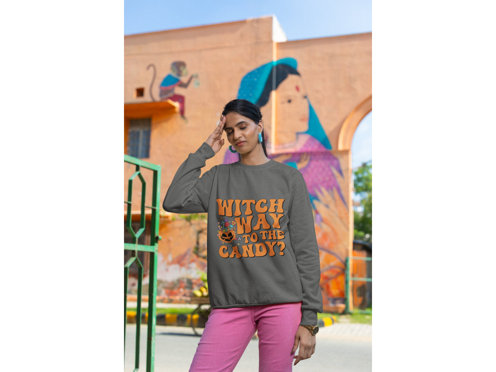 A woman wears a dark grey "Witch Way to the Candy?" Halloween sweatshirt.