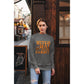 A woman wears a dark gray sweatshirt with "Witch Way to the Candy?" in orange text.