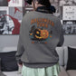 A person from behind wears a gray Halloween Town sweatshirt with a pumpkin graphic.