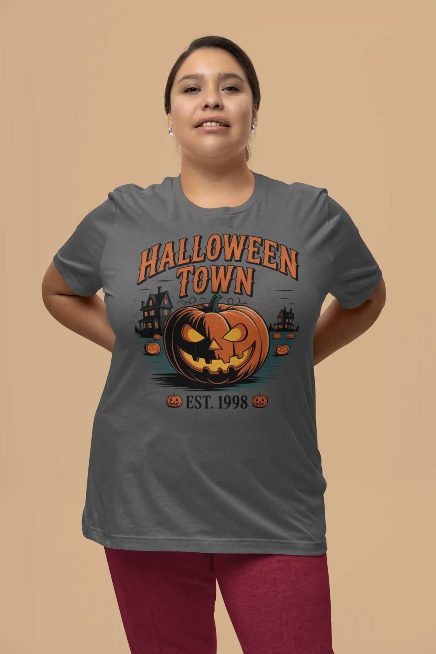 A woman wears a dark gray Halloween Town t-shirt with a pumpkin graphic.