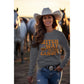 A woman in a cowboy hat and jeans wears a dark gray Halloween sweatshirt.