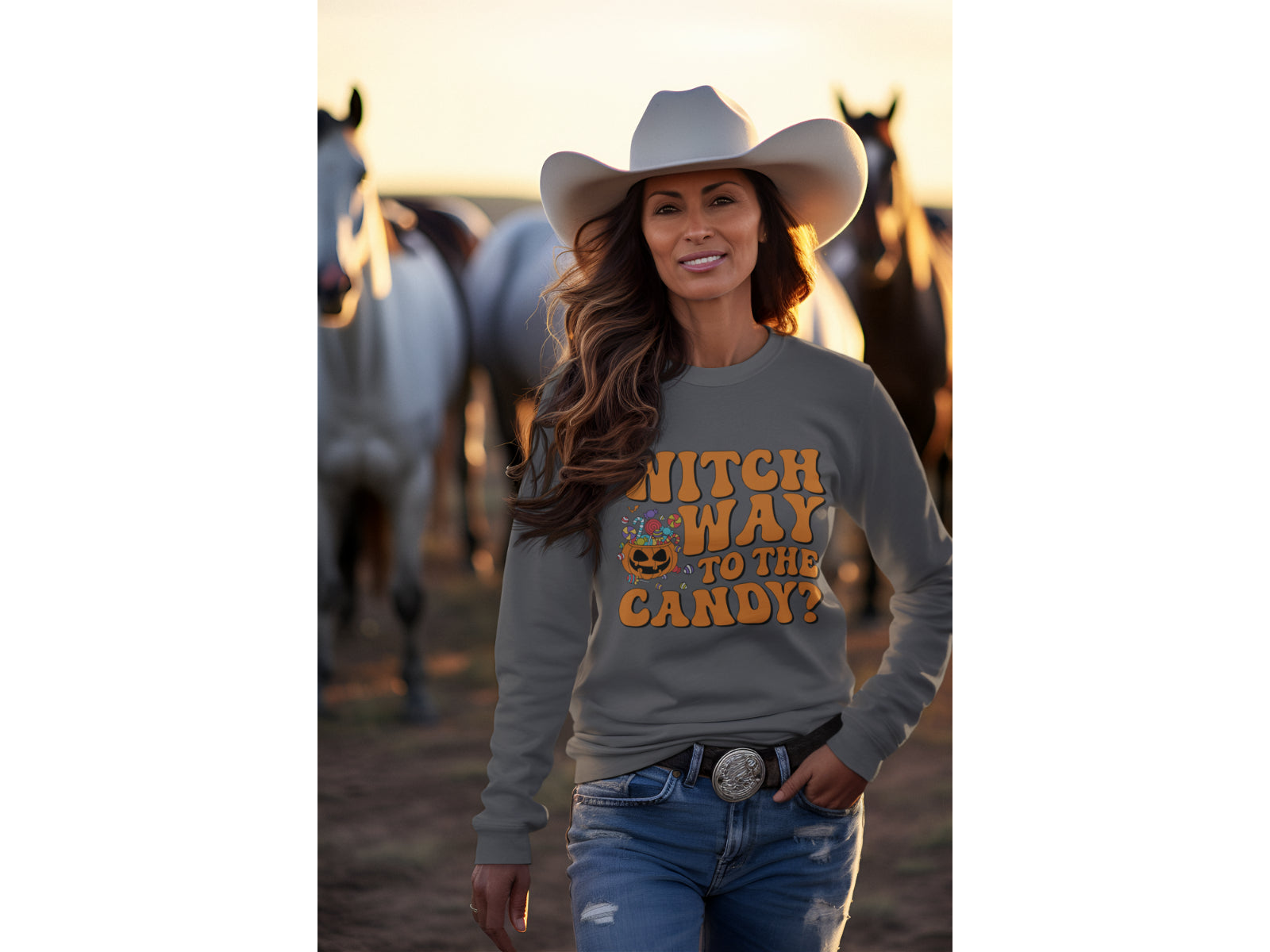 A woman in a cowboy hat and jeans wears a dark gray Halloween sweatshirt.