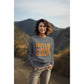 A woman wears a dark gray "Witch Way to the Candy?" Halloween sweatshirt.