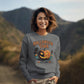 A woman smiles while wearing a gray Halloween Town sweatshirt with a vintage pumpkin graphic.