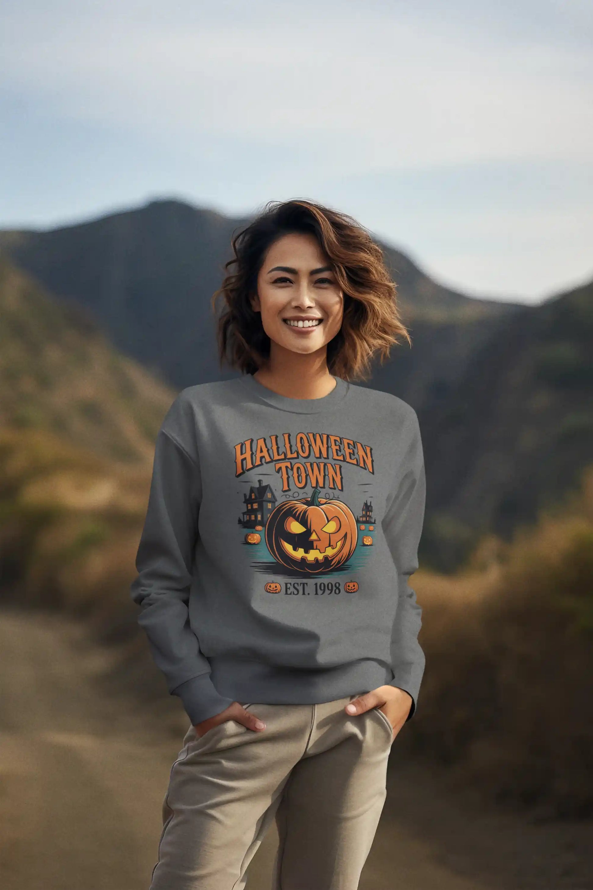A woman smiles while wearing a gray Halloween Town sweatshirt with a vintage pumpkin graphic.