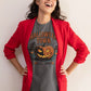 A woman in a red blazer wears a gray Halloween Town t-shirt with a pumpkin graphic.