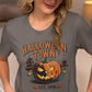 A woman in a baseball cap wears a gray Halloween Town t-shirt with a pumpkin graphic.