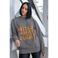 A woman wears a dark gray sweatshirt with "Witch Way to the Candy?" text.