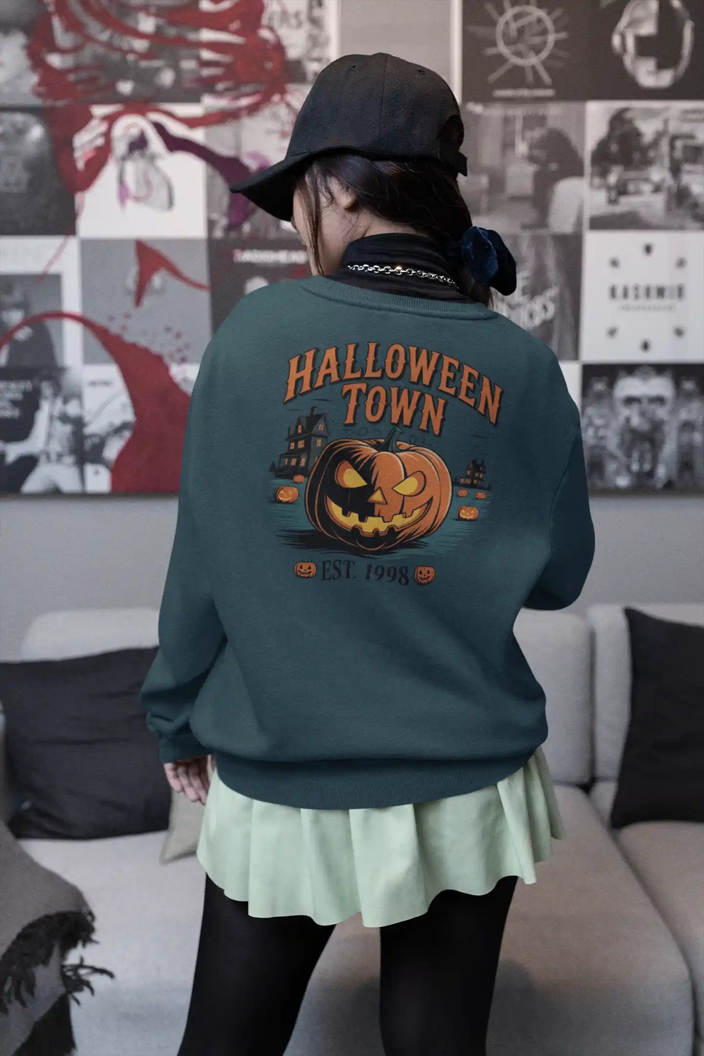 A person from behind wears a dark green Halloween Town sweatshirt with a pumpkin graphic.