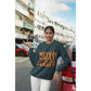 A woman wears a dark green "Witch Way to the Candy?" Halloween sweatshirt.