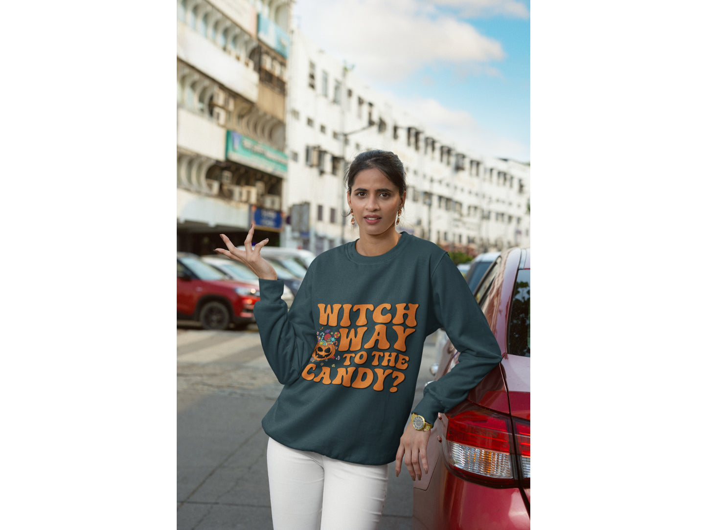A woman wears a dark green "Witch Way to the Candy?" Halloween sweatshirt.
