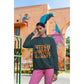 A woman wears a dark green "Witch Way to the Candy?" Halloween sweatshirt.