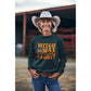 A smiling woman in a cowboy hat wears a dark green "Witch Way to the Candy?" sweatshirt.