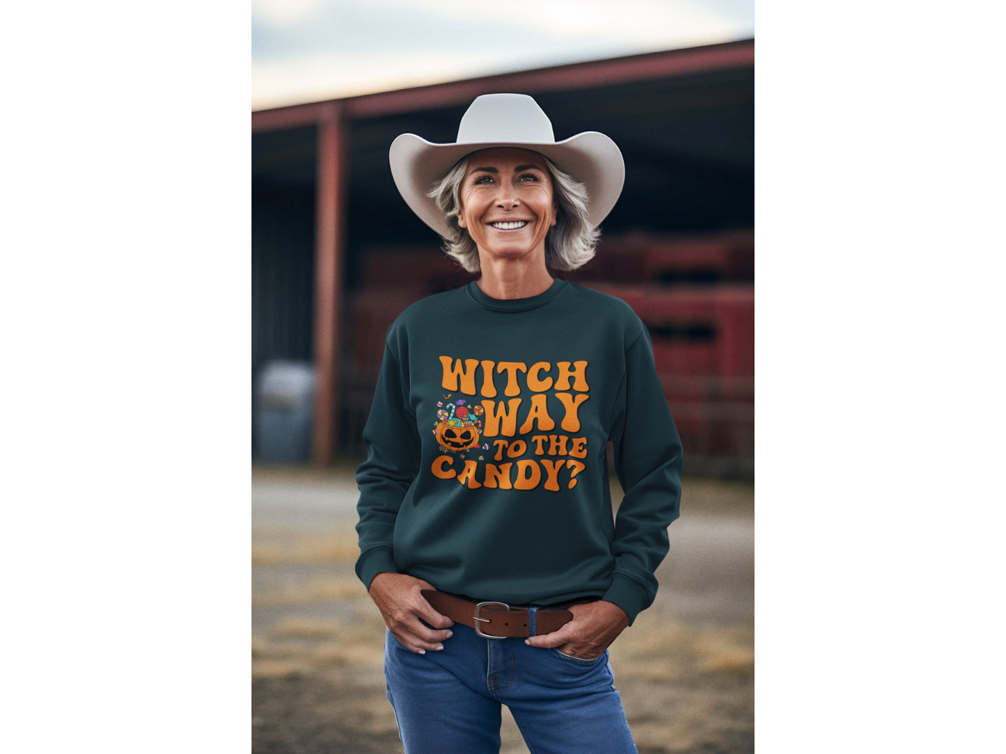A smiling woman in a cowboy hat wears a dark green "Witch Way to the Candy?" sweatshirt.