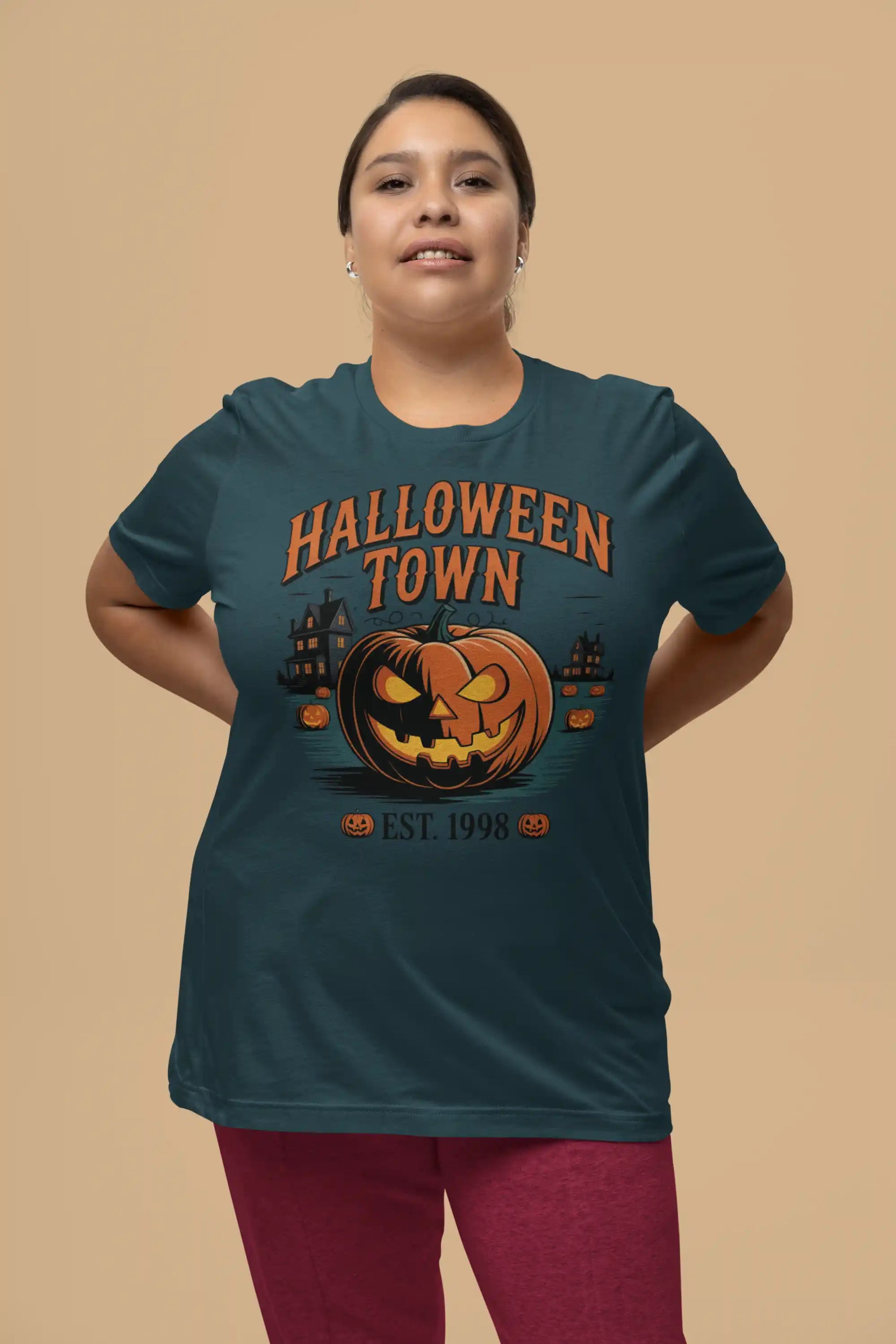 A woman wears a dark teal Halloween Town t-shirt with a vintage pumpkin graphic.