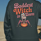 A person from behind wears a dark green sweatshirt with "Baddest Witch in Town" text.