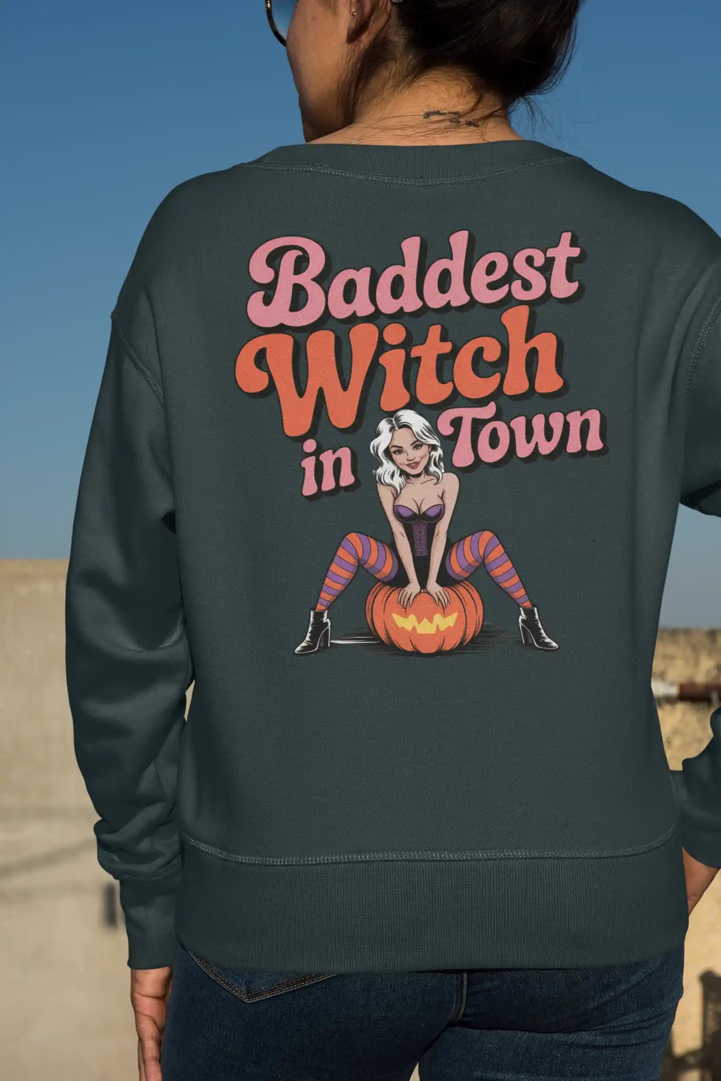 A person from behind wears a dark green sweatshirt with "Baddest Witch in Town" text.