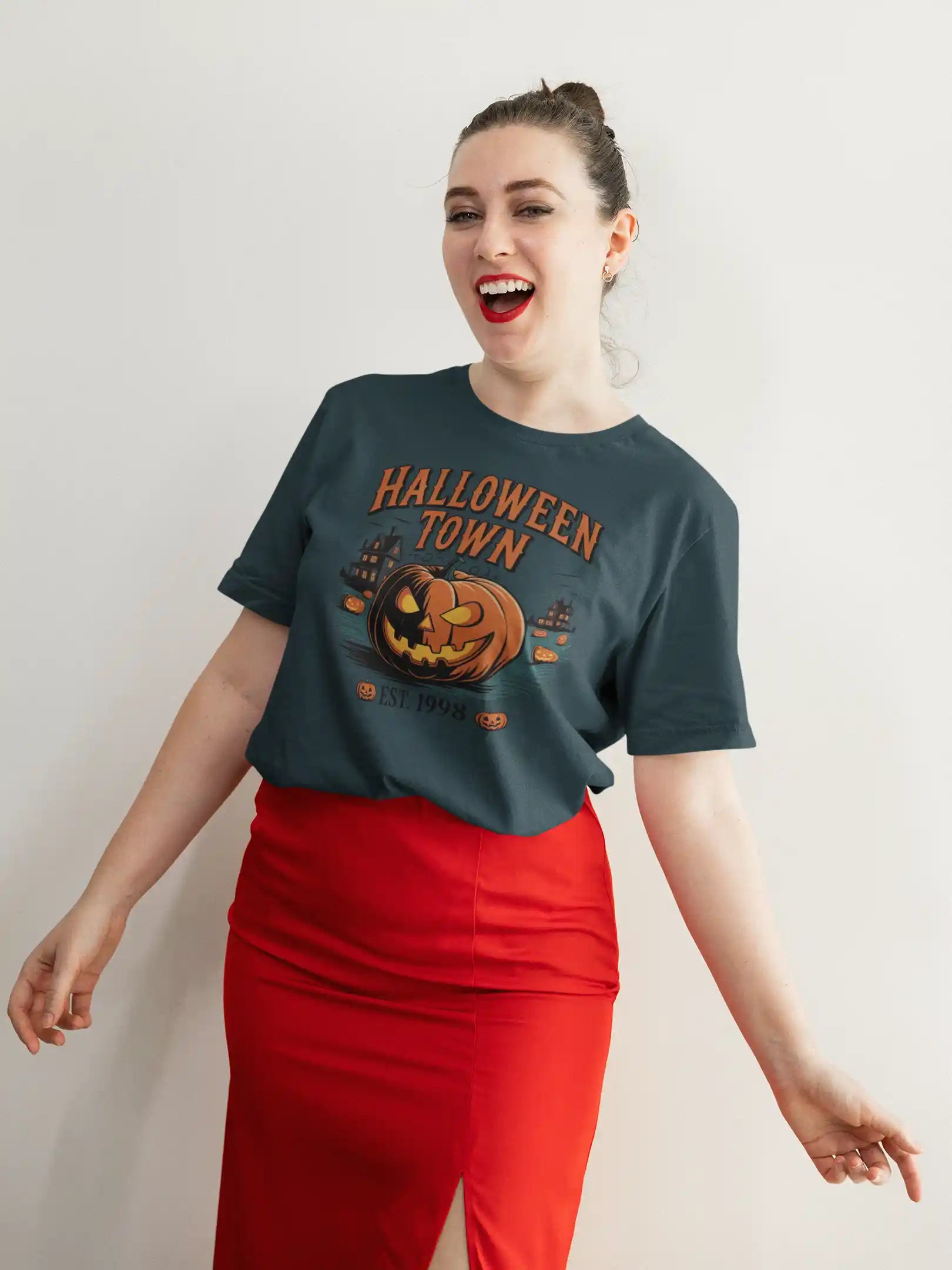 A woman smiles wearing a dark green Halloween Town t-shirt with a pumpkin graphic.