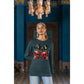 A woman wears a dark green long-sleeve shirt with a red skull and cherry design.