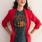 A woman in a red blazer wears a dark green Halloween Town t-shirt with a pumpkin graphic.