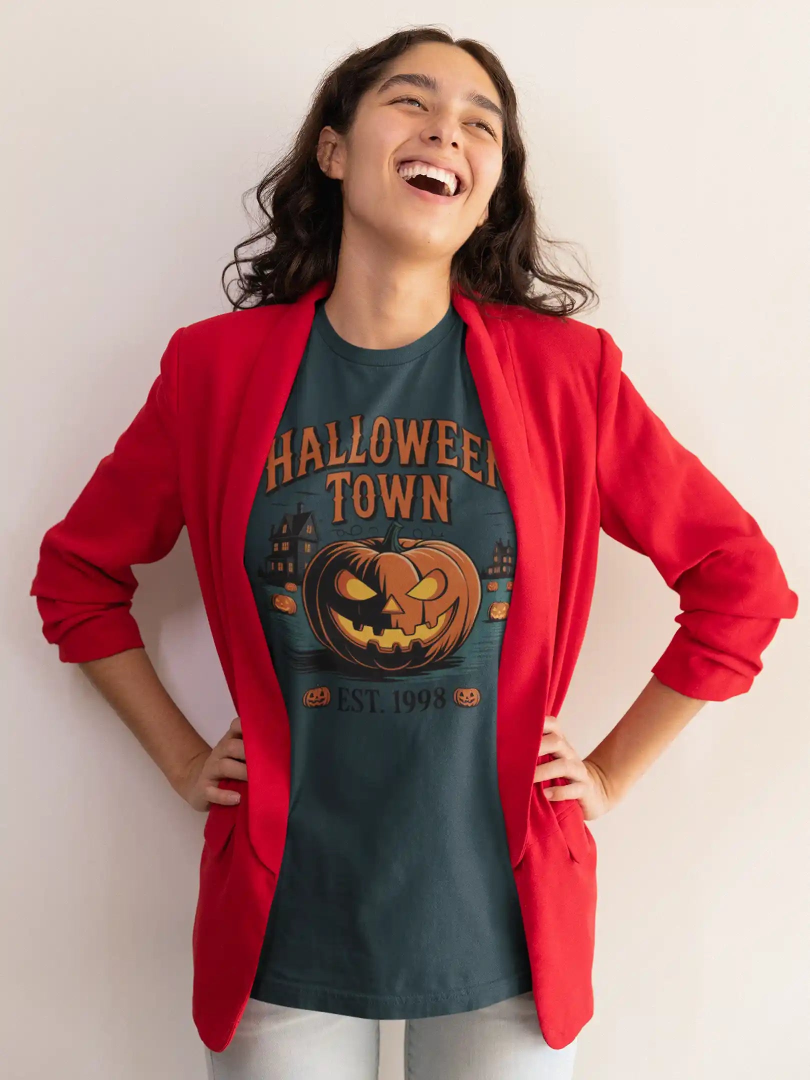 A woman in a red blazer wears a dark green Halloween Town t-shirt with a pumpkin graphic.