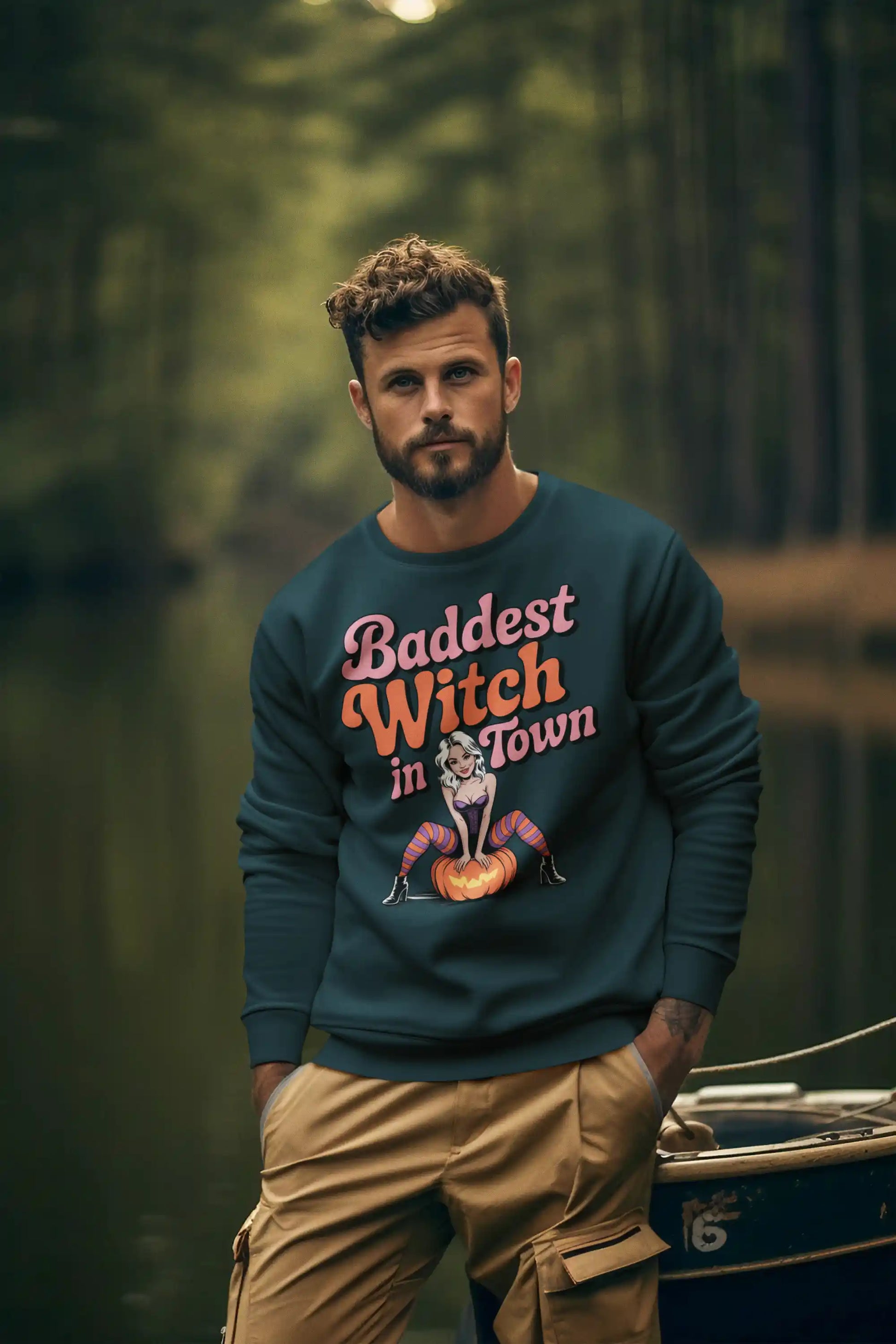 A man wears a dark teal sweatshirt with "Baddest Witch in Town" and a pin-up witch graphic.