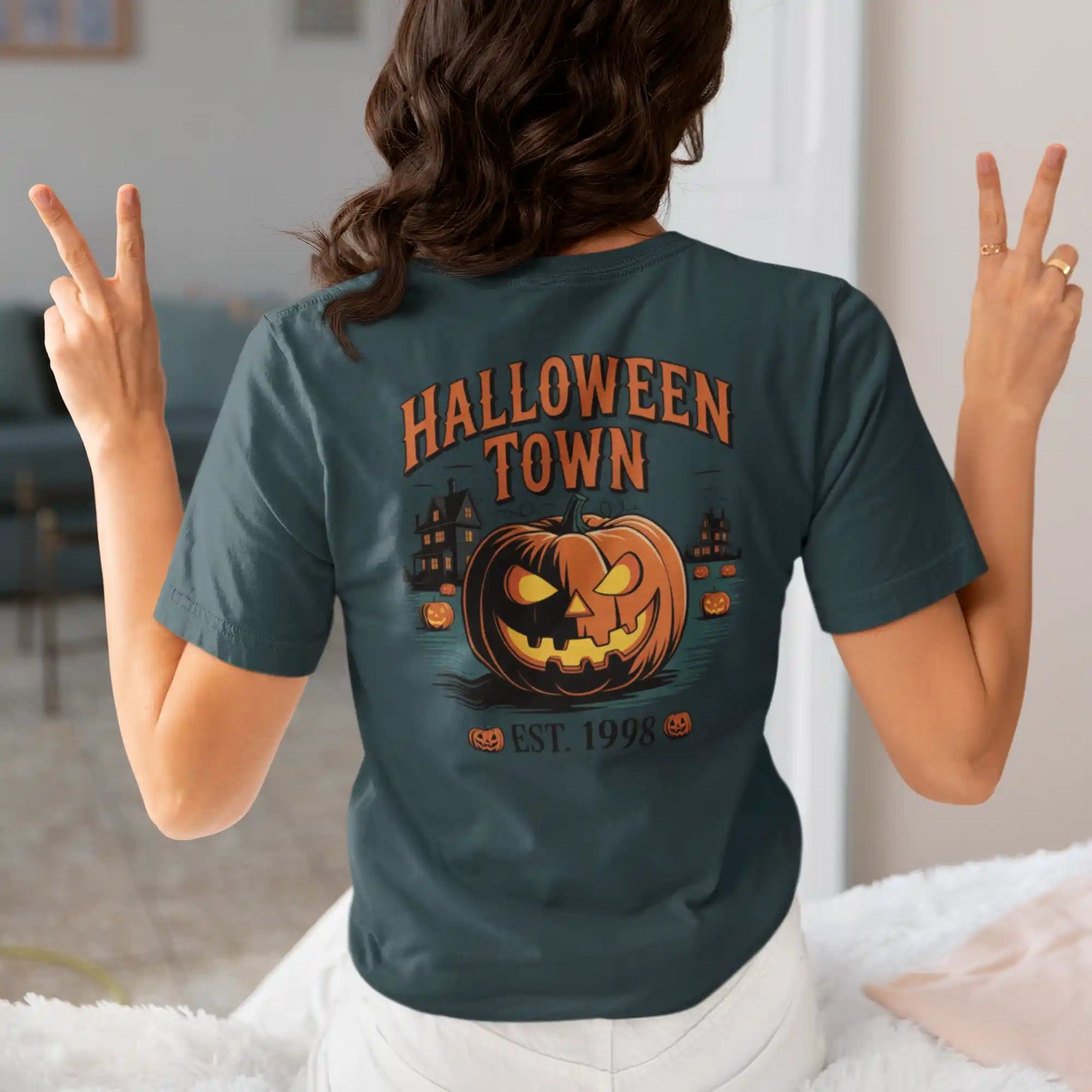A person from behind wears a dark green Halloween Town t-shirt with a pumpkin graphic.