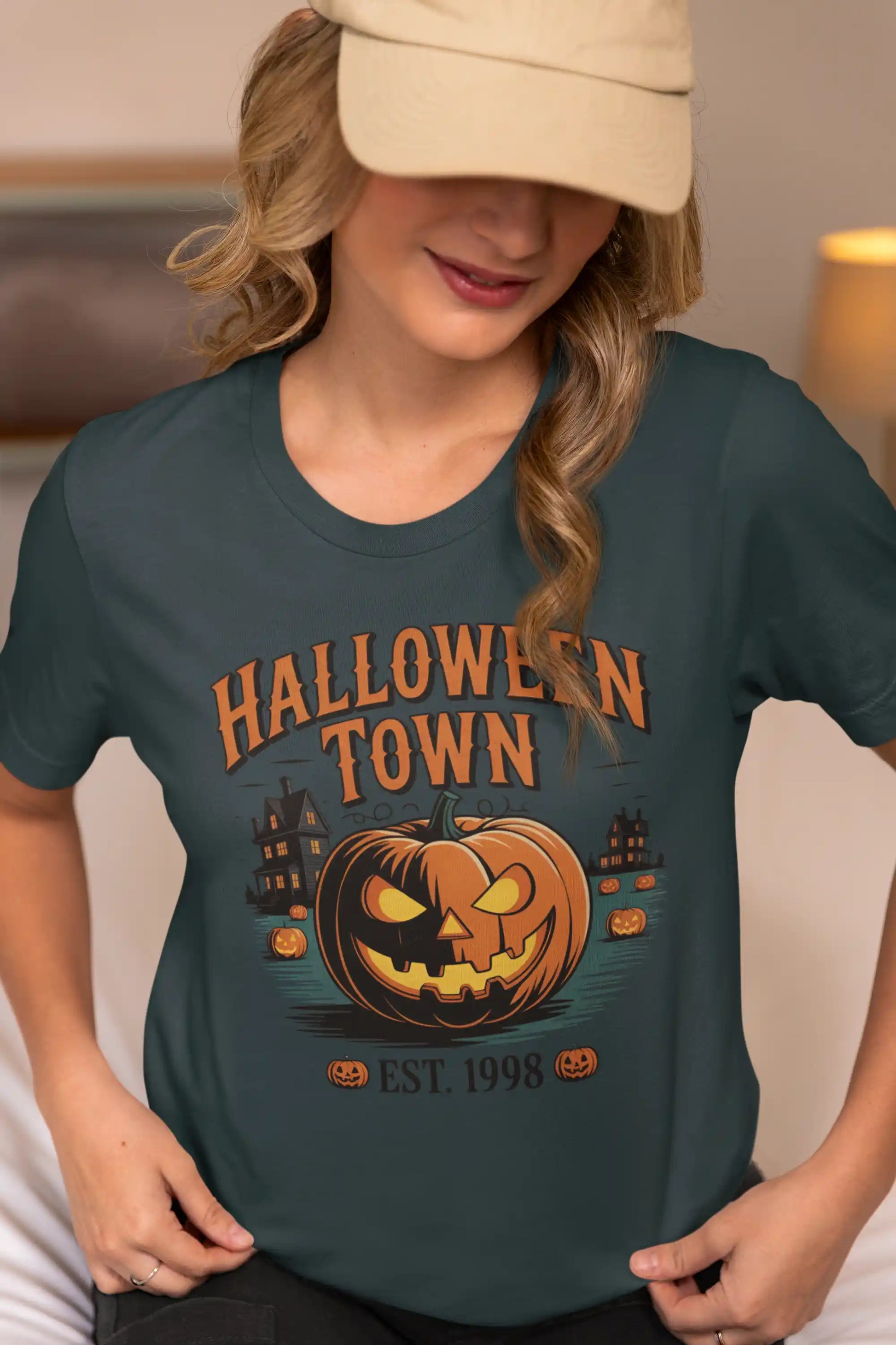 A woman in a baseball cap wears a dark green Halloween Town t-shirt.