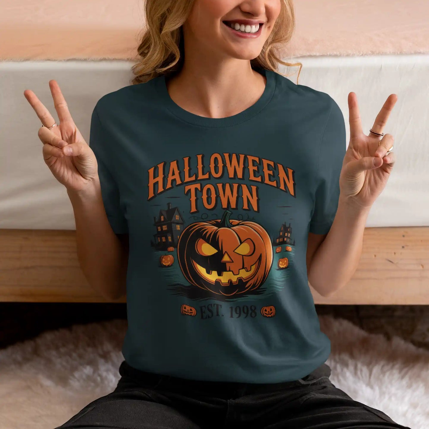 A woman in a dark teal Halloween Town t-shirt makes a peace sign.