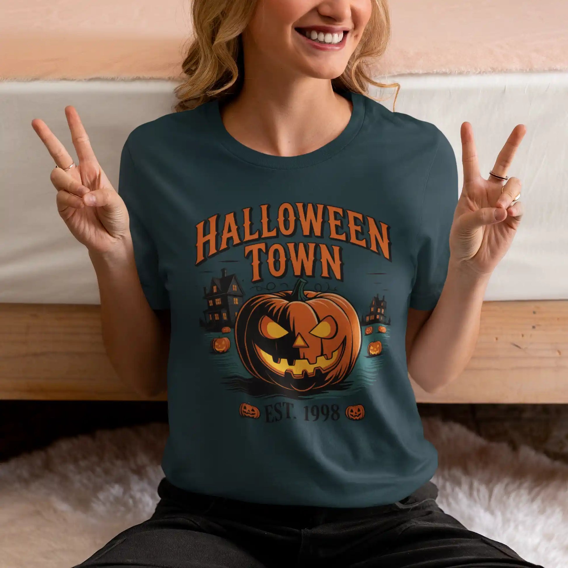 A woman in a dark teal Halloween Town t-shirt makes a peace sign.