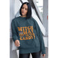 A woman wears a dark teal sweatshirt with "Witch Way to the Candy?" in orange text.