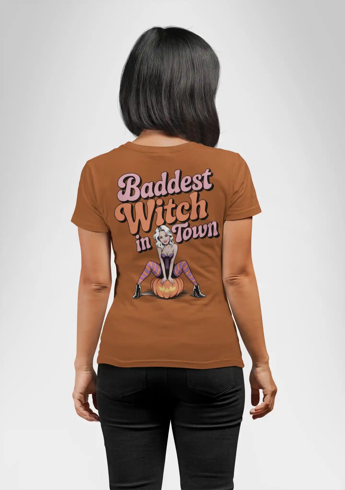 A woman from behind wears a brown t-shirt with "Baddest Witch in Town" and a witch graphic.